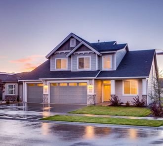 A suburban home at dusk with its lights on